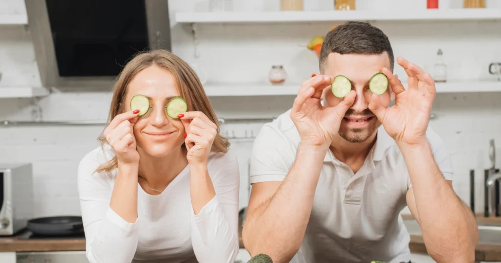 Imagen en la que podemos ver a una pareja joven con unas rodajas de pepino en los ojos haciendo una representación a los alimentos que protegen tu vista.