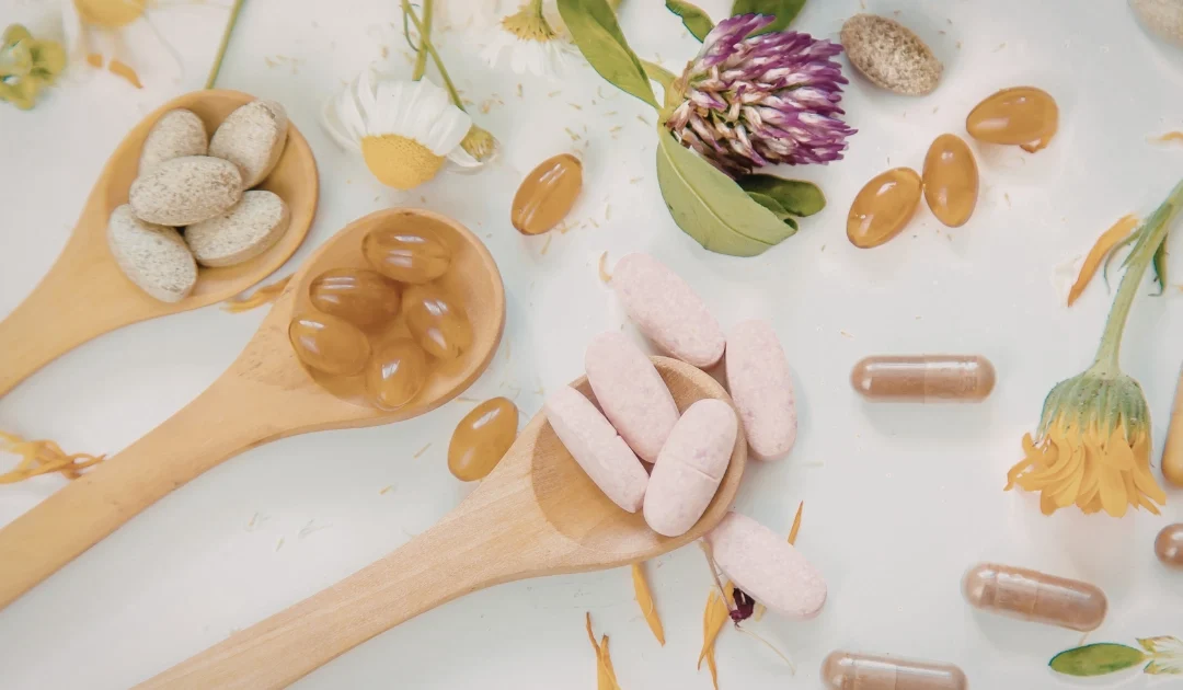 Mesa blanca con distintas opciones de suplementación deportiva natural en pastillas y fondo con plantas y flores