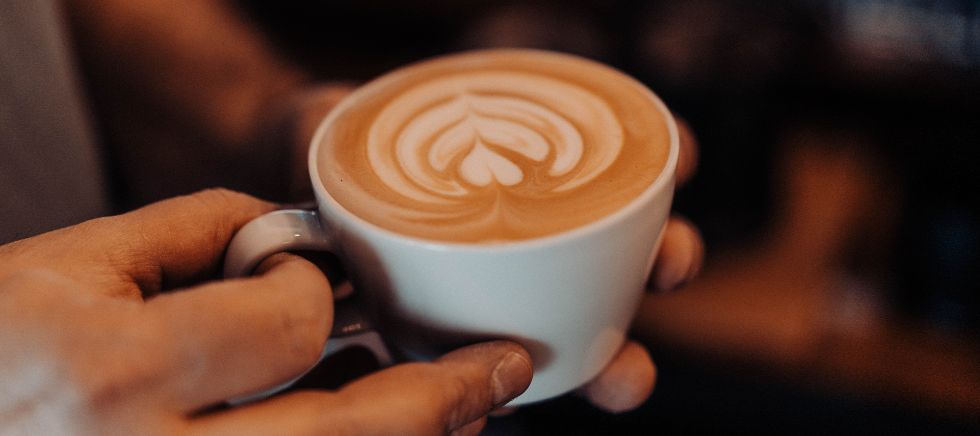 Persona con taza de café de cereales en la mano, presentando una textura cremosa y parecida al café tradicional.