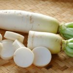 Daikon o nabo japonés sobre mesa de madera preparado para cocinar.