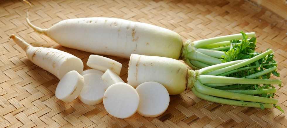 Daikon o nabo japonés sobre mesa de madera preparado para cocinar.