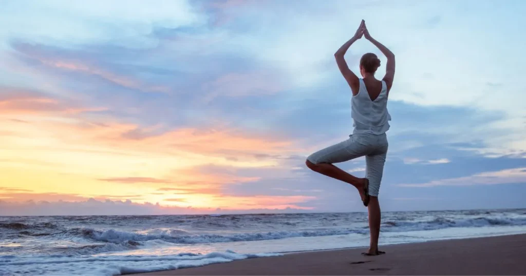 Mujer haciendo yoga en la playa para rehuir de las molestias estomacales.