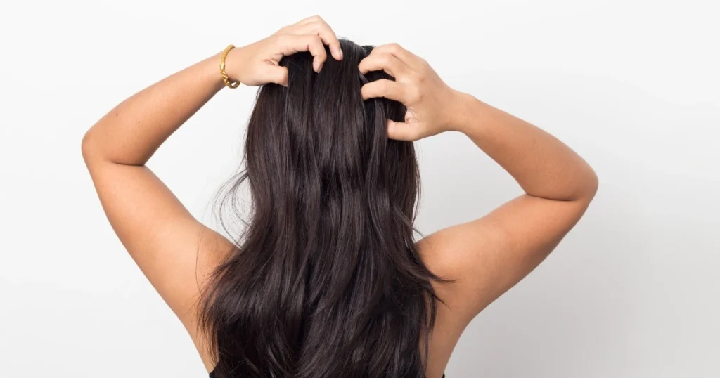 Mujer con las manos en la cabeza dado que no sabe lo que hacer para tener un pelo sano.