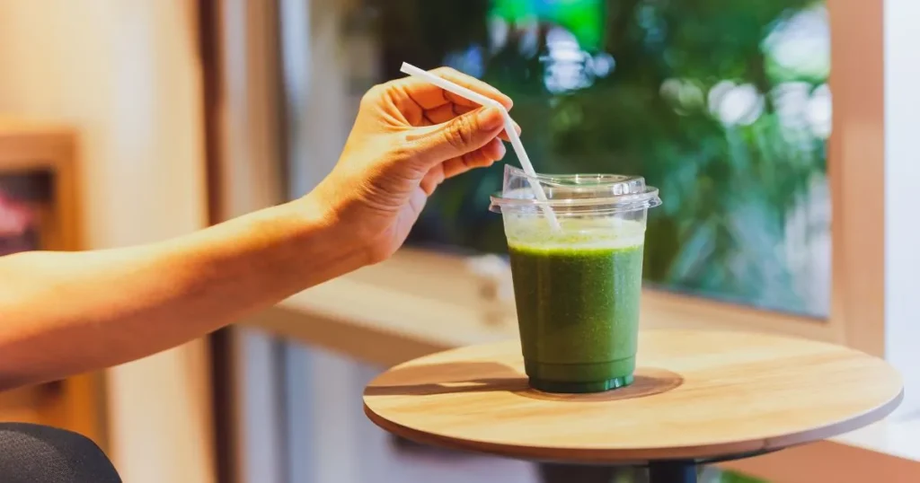 Bebida de kombucha verde en vaso de plástico con cañita para ejemplificar qué son los probióticos.