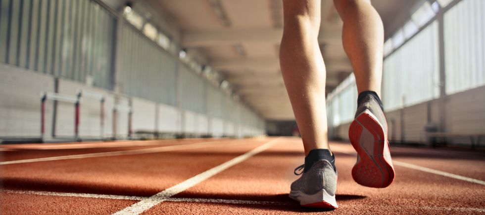 Deportista corriendo en pista de atletismo para demostrar las ventajas de las sales de magnesio en el deporte de fondo.